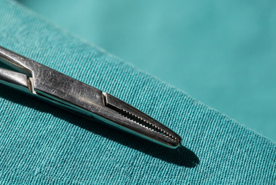 Surgical forceps on teal fabric with clean copy space