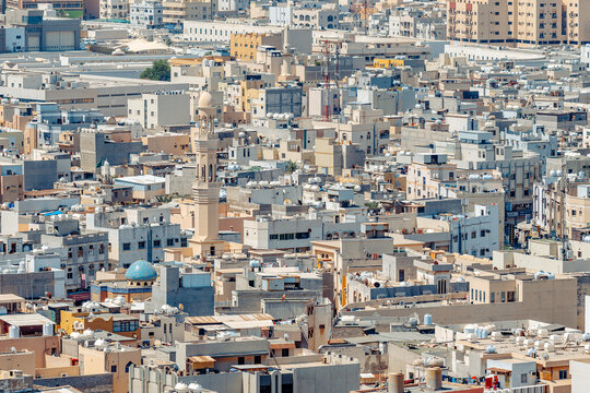 Aerial view of the dense urban cityscape featuring traditional architecture, a prominent minaret, and flat rooftops, Manama, Capital Governorate, Bahrain.
