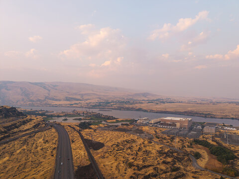 Aerial view of the Google Data Center near the Columbia River surrounded by arid landscape and hazy, smoke-filled sky in The Dalles, Oregon, United States.
