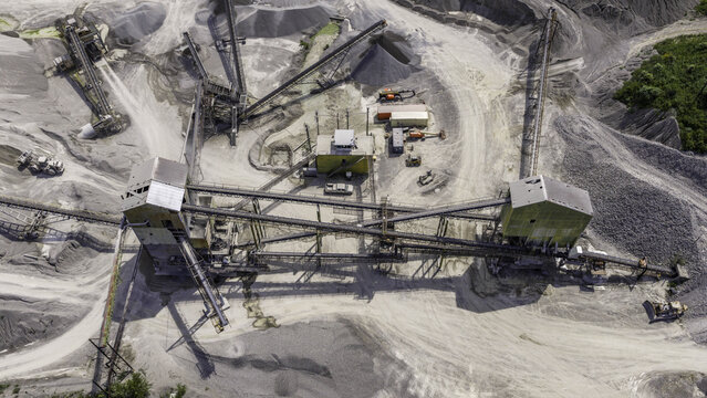 Aerial view of an aggregate processing plant with conveyor belts, heavy machinery, and stepped quarry walls in Clarksville, Tennessee, United States.