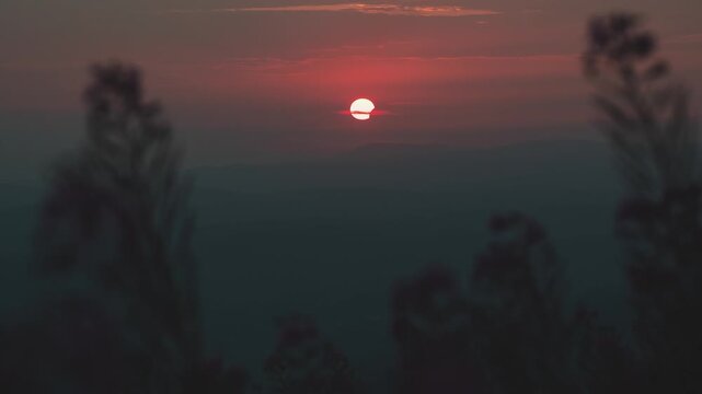 Timelapse video of a partial solar eclipse during sunset viewed from Babin Zub peak on Stara Planina mountain, Serbia. Cinematic shot showing the moon covering the sun against a warm orange sky with d