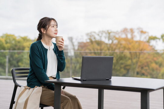 屋外テーブルでノートパソコンと休む女性の秋時間と通勤風景