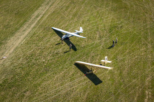 Lososina Dolna, Poland - 14 August 2026: Aerial view of Aeroklub Podhalanski im. Leopolda Kwiatkowskiego with gliders parked on the grassy airfield and people standing nearby.
