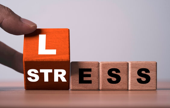 Hand turns a wooden block to change STRESS into LESS symbolizing stress reduction, mental wellness, positive change, problem solving, balance and managing pressure for a healthier lifestyle.