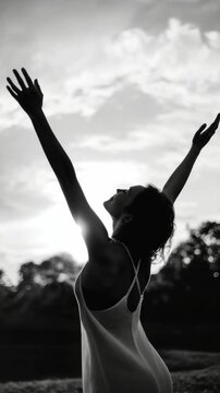 Silhouette of Woman with Arms Raised in Backlit Outdoors