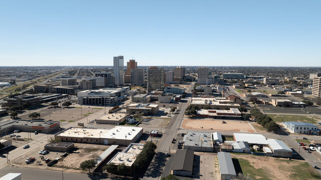 Midland, Texas, United States - 16 December 2023: Aerial view of the Midland skyline featuring commercial buildings, urban streets, and parking lots under a clear blue sky.