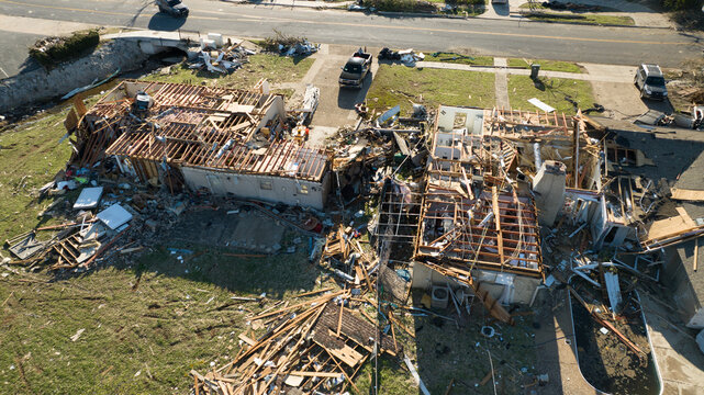 Little Rock, United States - 21 March 2023: Aerial view of severe tornado damage to residential homes with scattered debris, exposed roof structures, and damaged vehicles.