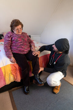 A man young doctor provides medical care at an elderly woman's home