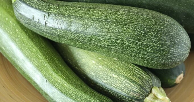 Many fresh raw zucchinis spinning on plate, closeup