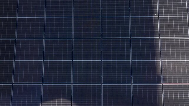AERIAL TOP DOWN: Large photovoltaic system covering the red roof of a countryside home. Rows of solar panels form geometric pattern beside a green garden and lawn. Domestic renewable energy production