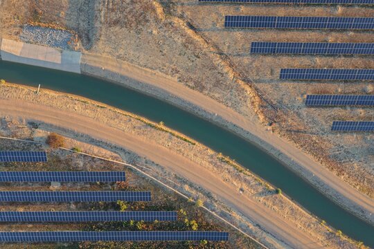 Aerial view of Boulder Reservoir with rows of solar panels installed along a water canal in the arid landscape of Boulder, Colorado, United States.