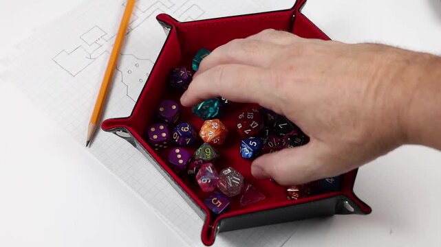 Rolling polyhedral gaming dice into a dice tray. Various colors and denominations of dice. 