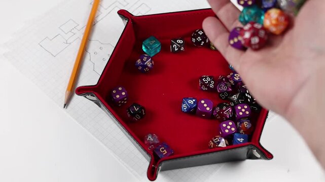 Rolling polyhedral gaming dice into a dice tray. Various colors and denominations of dice. 
