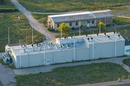 Aerial view of a pharmaceutical laboratory facility featuring external chillers and lightning protection rods on its metal roof, situated in Poland.