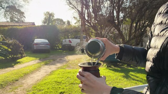 Close Up of Yerba Mate Drink Preparation a Winter day in the Garden, Pouring Hot Water Argentina, Tradition, Latin Heritage, Uruguay Paraguay and Brazil typical social beverage, Family Gathering