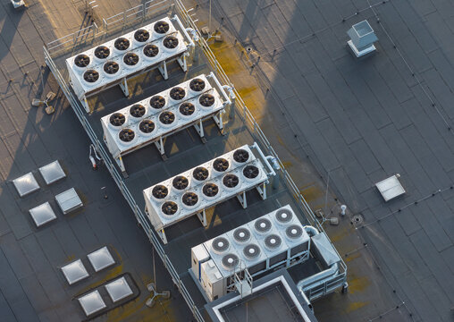 Aerial view of industrial HVAC cooling units on a data center rooftop with metal structures and shadows in Gdansk, Pomeranian Voivodeship, Poland.