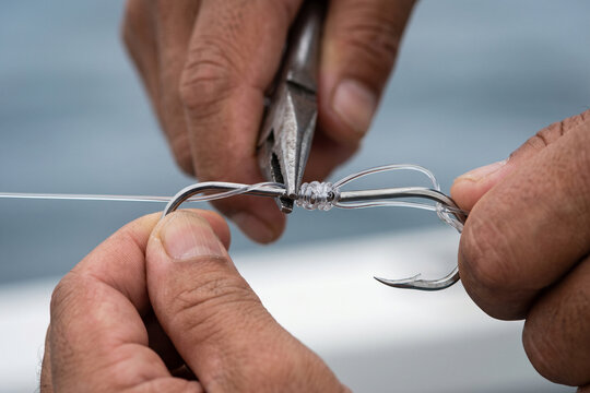 ペンチを使って鋭い釣り針とラインを丁寧に結束する手元