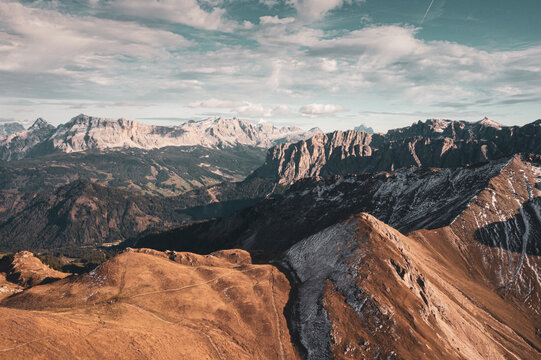 Aerial view of the rugged Dolomites mountain range near the Schluterhutte, featuring dramatic rocky peaks, steep slopes, and alpine terrain in Funes, Trentino-Alto Adige, Italy.