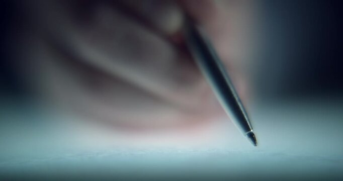 Extreme close-up footage of a man's hand signing an important document with a pen, captured with a shallow depth of field and cinematic focus. Conceptual footage representing contracts and agreements