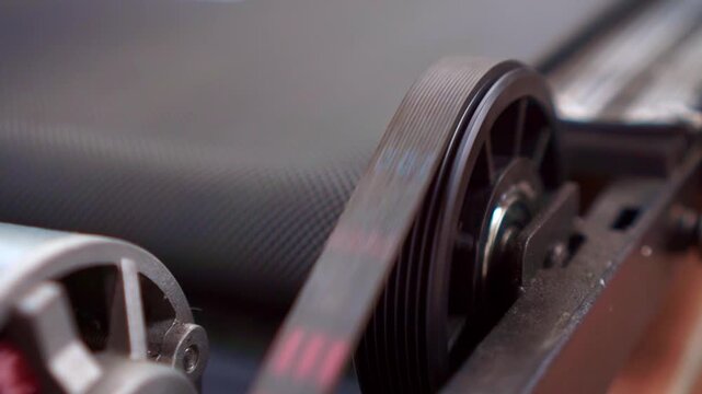 Industrial belt drive system with spinning pulley wheels, close up view, mechanical machine parts, engineering technology footage scene.