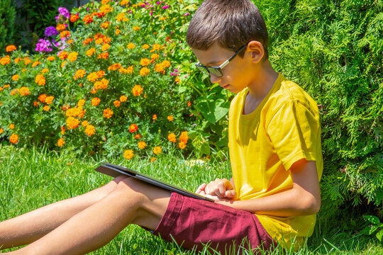Young boy watching movies on tablet in a park alone