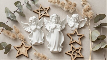 Fototapeta premium Three white angel figurines surrounded by wooden stars and dried eucalyptus leaves.