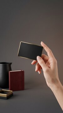 Hand holding small blackboard with gold trim against gray background