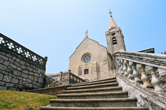 Low angle view of ancient Portuguese Our Lady of Penha Chapel with stone stairs during sunny summer day in Macau landmarks travel destination