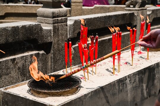 Burning red ritual joss stick incense candles with smoke and flame inside historic ancient A-Ma Temple built in 1488 in Macau China