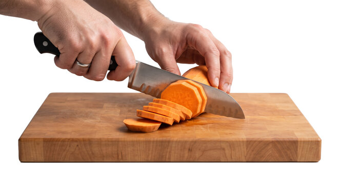 PNG cut out isolated background. A close-up shot of a person's hands using a chef knife to slice fresh sweet potato on a wooden cutting board against an isolated black background.