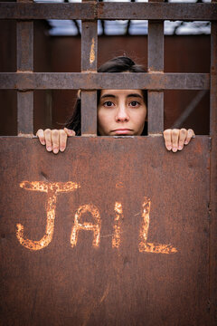 Woman looking through the bars of an old jail door