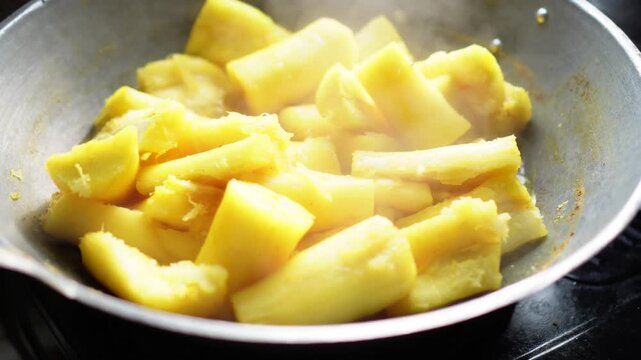 Golden pineapple chunks steaming in a metal wok during cooking. Close-up shot highlighting vibrant color and steam rising. Ideal for food preparation, healthy eating, or tropical cuisine concepts.
