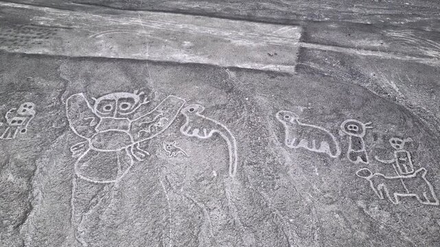 Ancient petroglyphs etched on rock surface showing stylized animals and human figures.