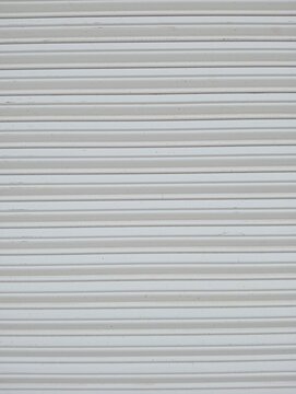 White roller shutter texture. Clean horizontal corrugated metal garage door surface close up. Minimalist industrial background pattern for security, storage, and architectural design concepts.
