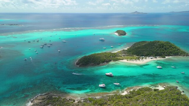 High altitude parallax sweeps across Tobago Cays' turquoise channels linking Petit Rameau, Jamesby and Baradal as yachts scatter the reef below
