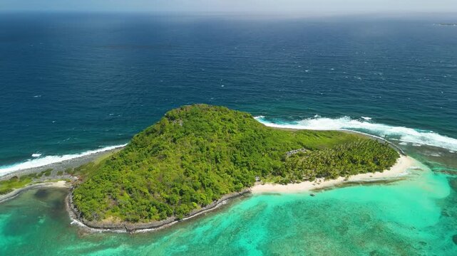 Aerial orbit reveals lush green Sandy Island fringed by white sand beach and turquoise coral reef lagoon off coast of Grenada, Caribbean
