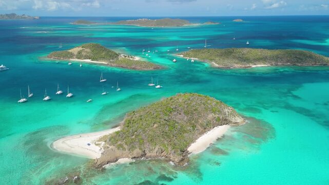 Aerial orbit circles Baradal's sandy point as sailboats anchor near Petit Rameau and Jamesby islets across Tobago Cays' turquoise reefs