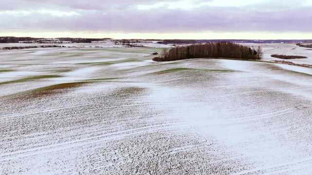 Drone pulls away revealing lightly snow covered rolling hills, Tukums region