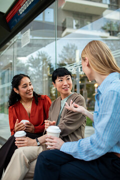 Friends chatting over coffee at bus stop