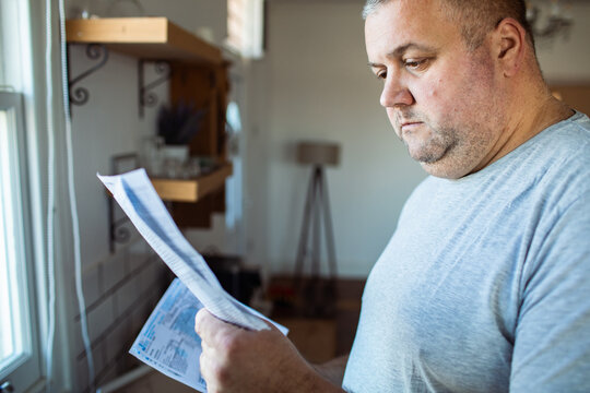Concerned man reading utility bills at home