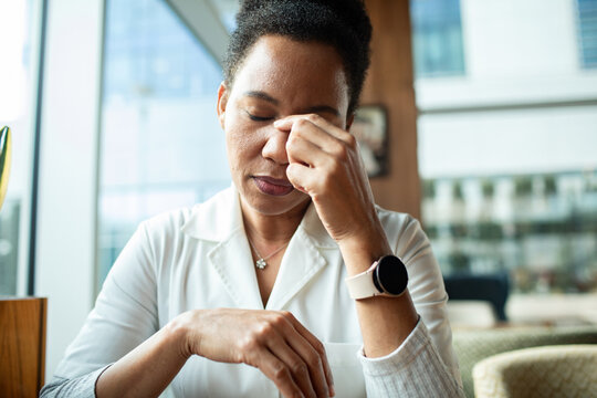 Stressed professional woman rubbing eyes in office