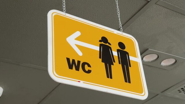 Close up of yellow Restroom Directional Sign hanging on the ceiling Inside Fast Food Restaurant