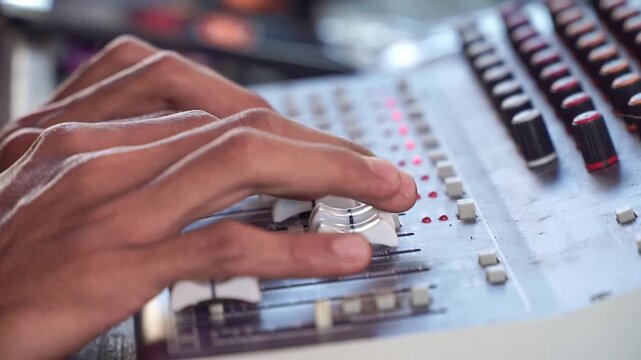 fingers adjusting mixing board controls, sound engineering equipment, music production and audio concept.