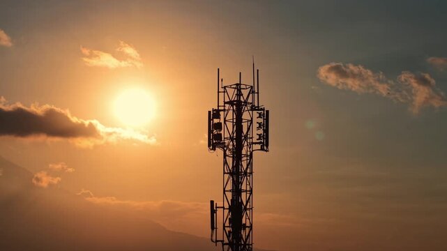 Silhouette of telecommunications tower during golden hour sunset. Network, connectivity, and technology infrastructure concept footage sky background.