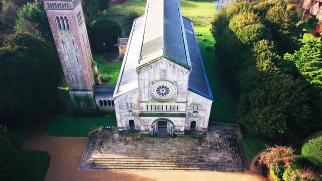 Aerial drone footage of a close up view of a parish church facade with a rose window Italianate detailing and a separate bell tower