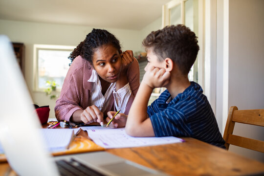 Parent tutoring child with homework at kitchen table
