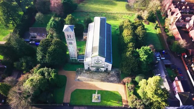 Aerial top down drone footage of Wilton parish church and its bell tower with the churchyard grounds and a roadside war memorial