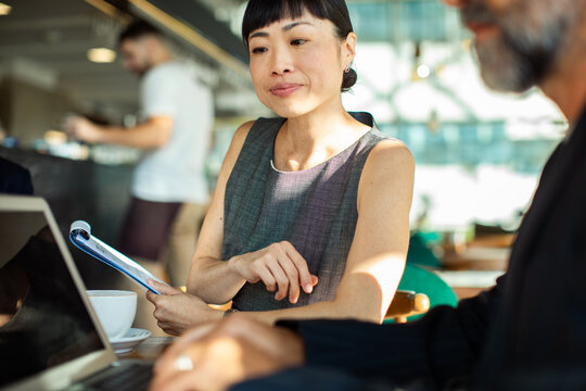 Businesswoman reviewing report with colleague in cafe