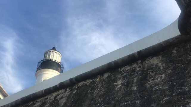 Low angle view of the historic Farol da Barra, a famous lighthouse and landmark in Salvador, Bahia, Brazil, revealing itself from behind the ancient walls of the Forte de Santo Ant&ocirc;nio da Barra