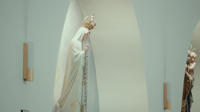 Statue of Our Lady of Fatima with golden crown and rosary praying inside a church niche